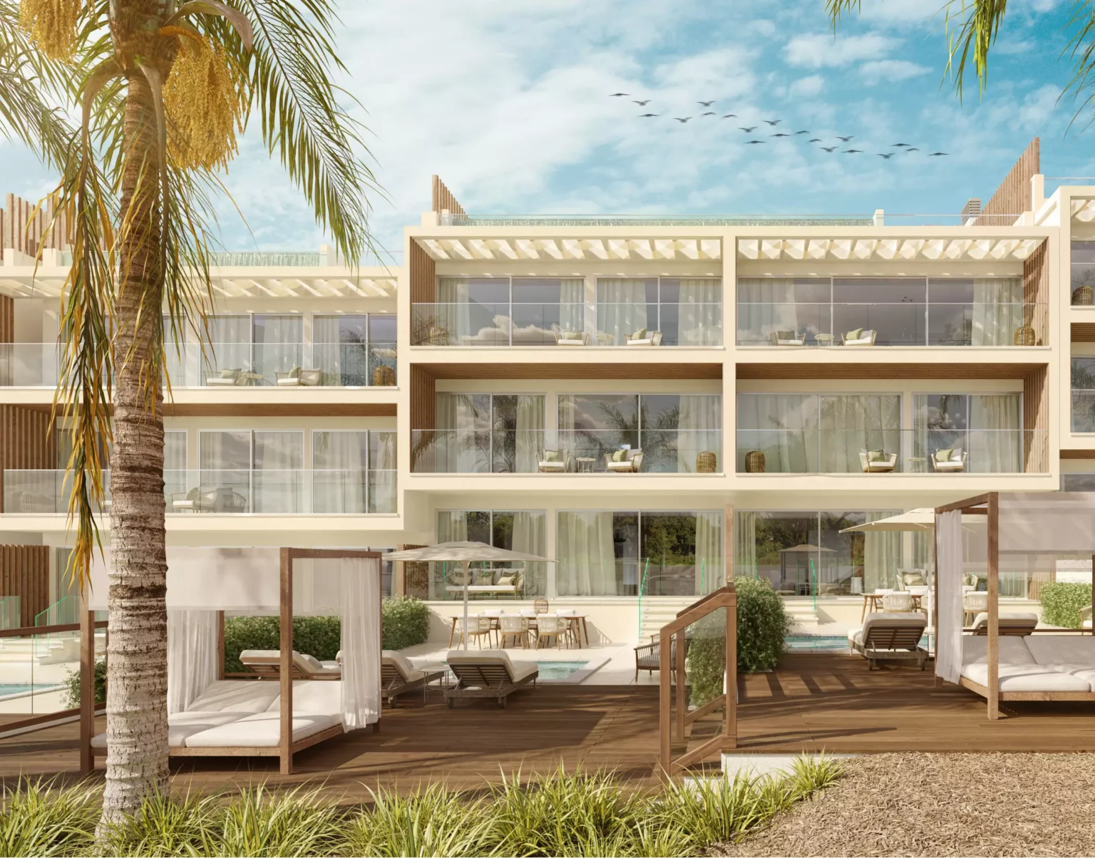 THE V apartments' façade, seen from an angle that highlights its outdoors, featuring swimming pools, palm trees, lounge areas and the blue sky.